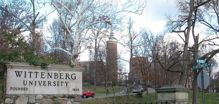 Entrance to Wittenberg University with a sign stating "Wittenberg University Founded 1845" in the foreground and campus buildings in the background, highlighting the institution's long-standing history and its commitment to excellence, as reflected in its comprehensive common data set.