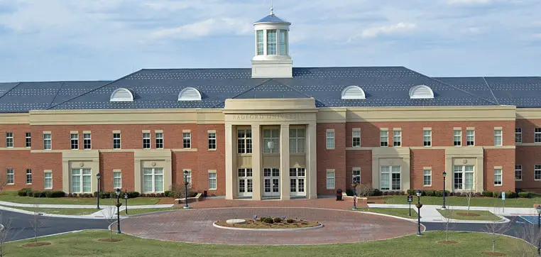 A large, two-story brick building with a prominent central entrance and cupola, surrounded by a circular driveway and landscaped area, reminiscent of the architectural charm found at Radford University.