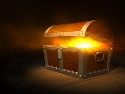 A wooden treasure chest is slightly open with a bright, golden light emanating from inside, casting a glow around the chest, much like the excitement one feels when they find merit scholarships.