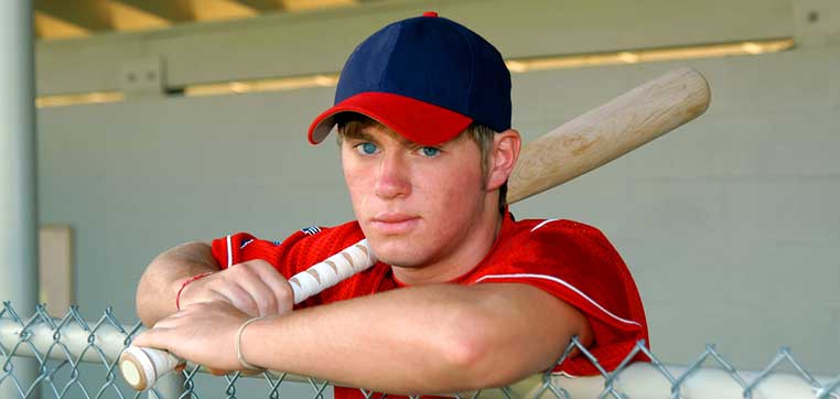 Baseball player in dugout representing college baseball camps and showcases