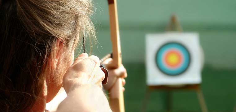 student aiming bow at target representing best colleges for financial aid